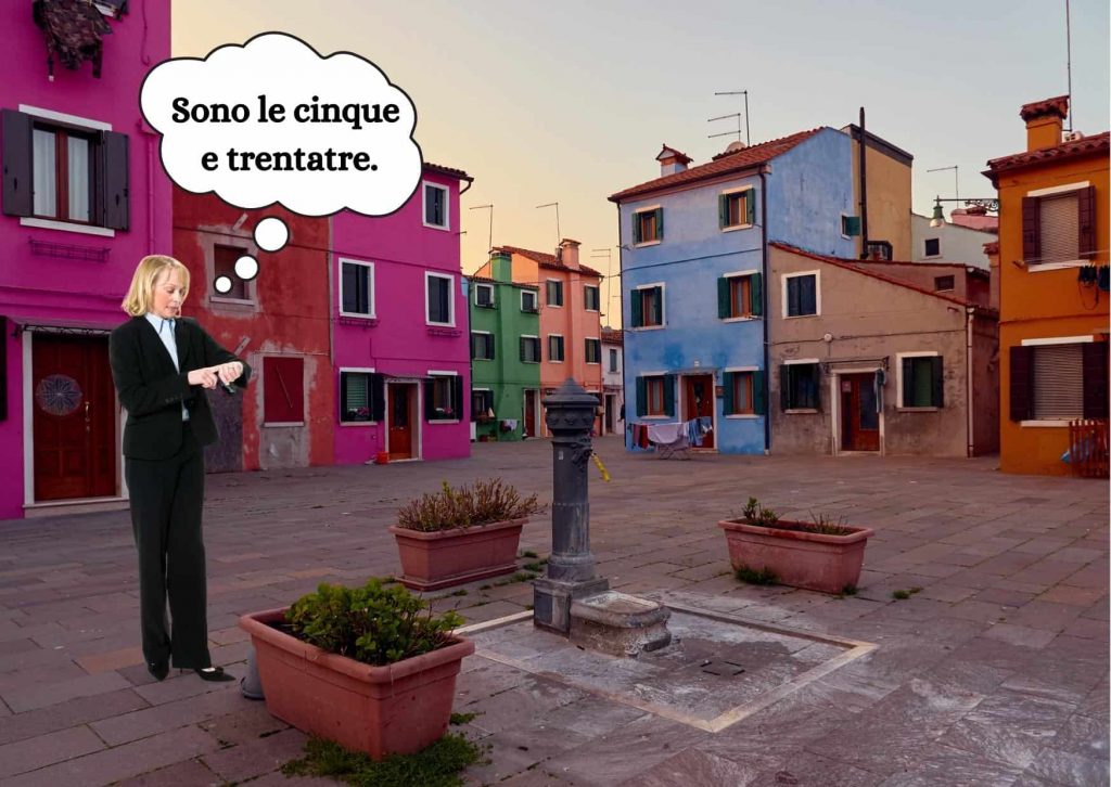 Woman in suit looking at time in Italian village.  The houses are colorful.  She has a graphic thought bubble near her head with "Sono le cinque e trentatre."  There is a water fountain next to her and some planters.