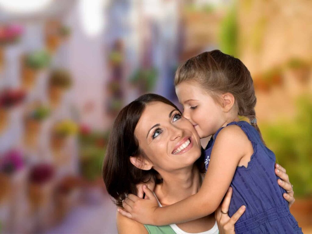 Mom and child hugging with a backround of a colorful Italian village.