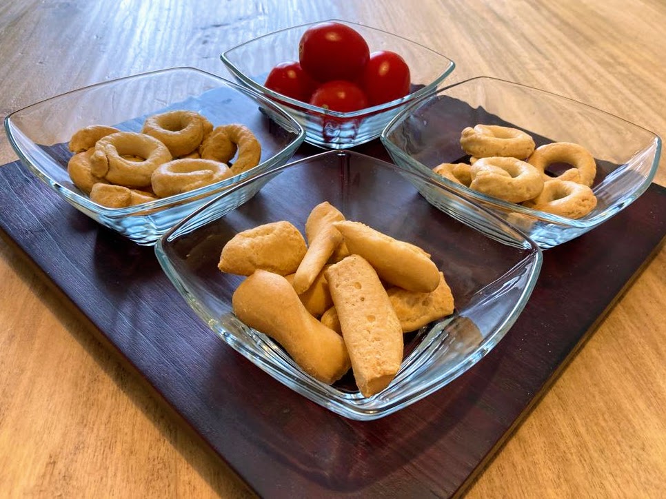 Italian brand Bormiolo Rocco snack dishes on a table with finger foods - taralli, tomatoes, and grissini.