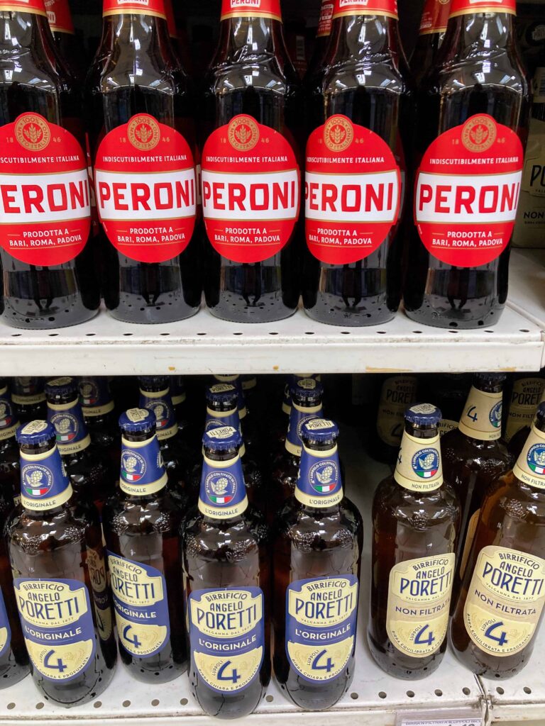 Peroni and Angelo Poretti beer on display at a grocery store in Italy.