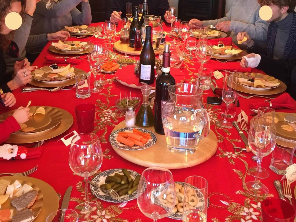 People sitting at table with red tablecloth for Christmas dinner in Italy