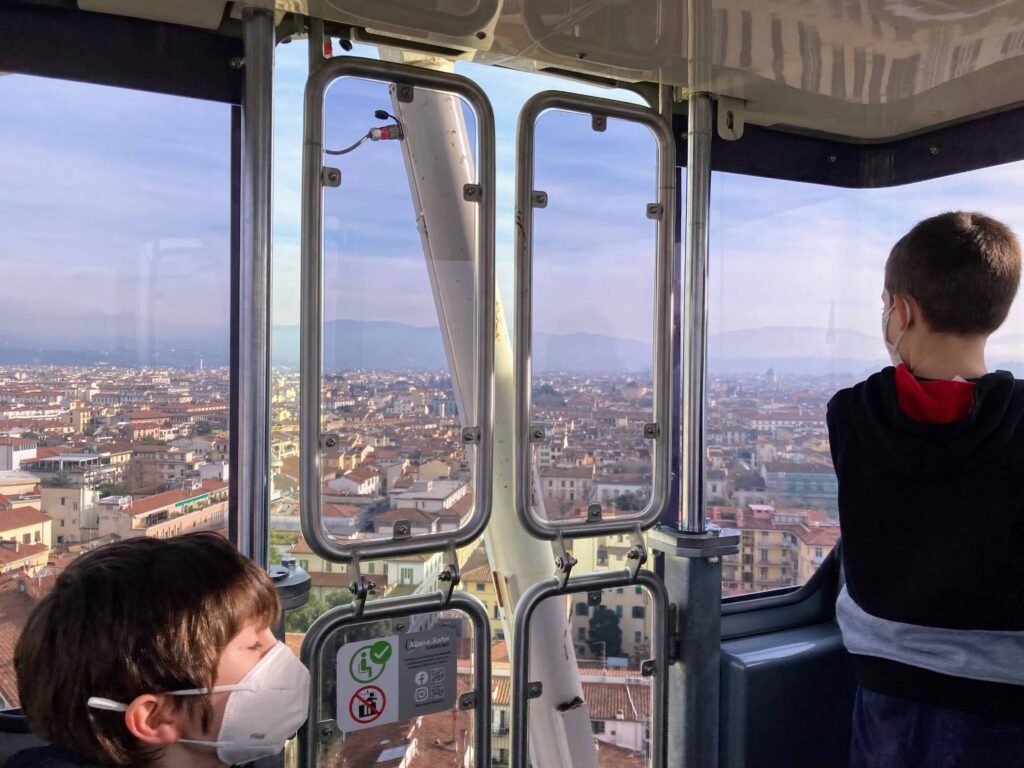 Two boys look out windows of a ferris wheel to see Florence down below.