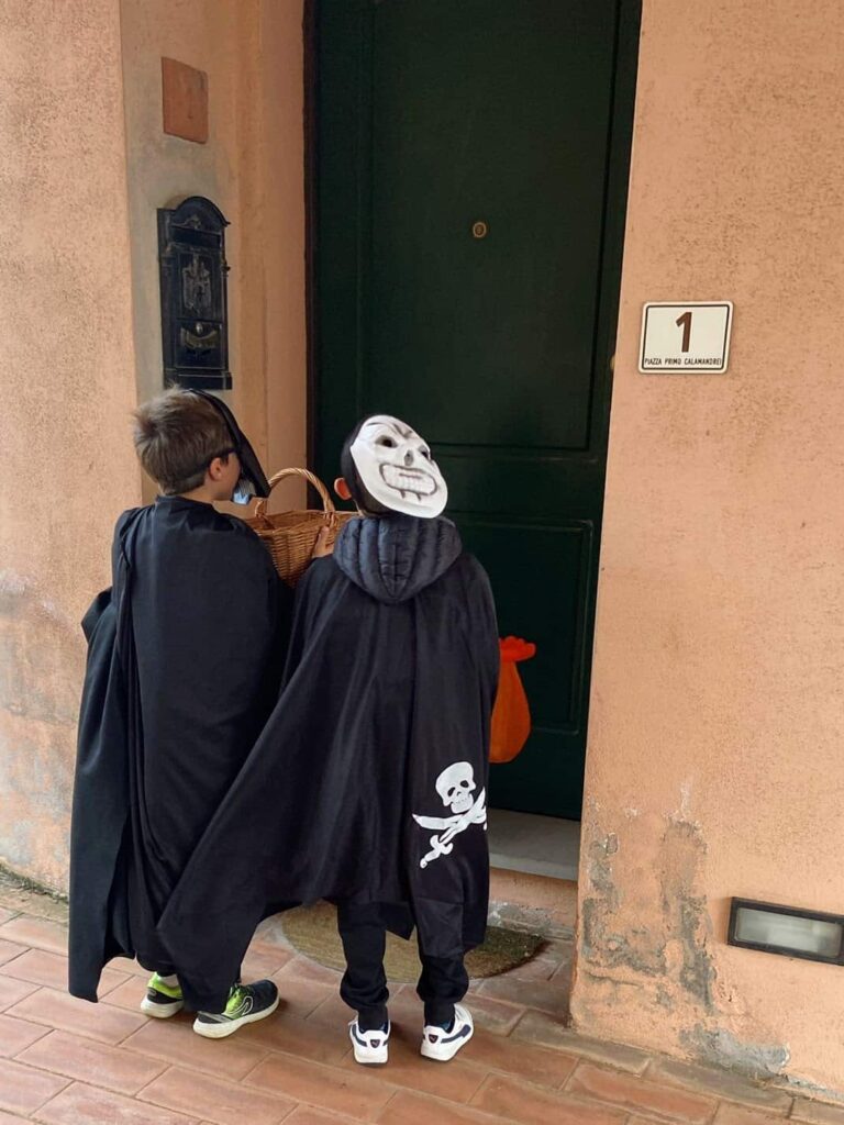 Children dressed in Halloween costumes knocking on a door in Italy
