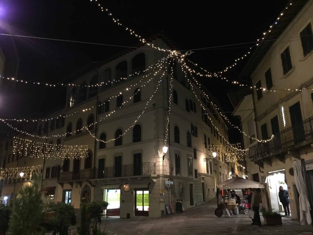 Christmas lights twinkle at night in a small square in a Tuscan village.