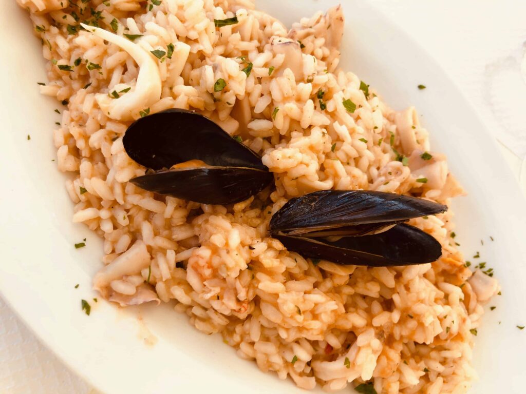 Close up of plate of seafood risotto with two mussels on top.