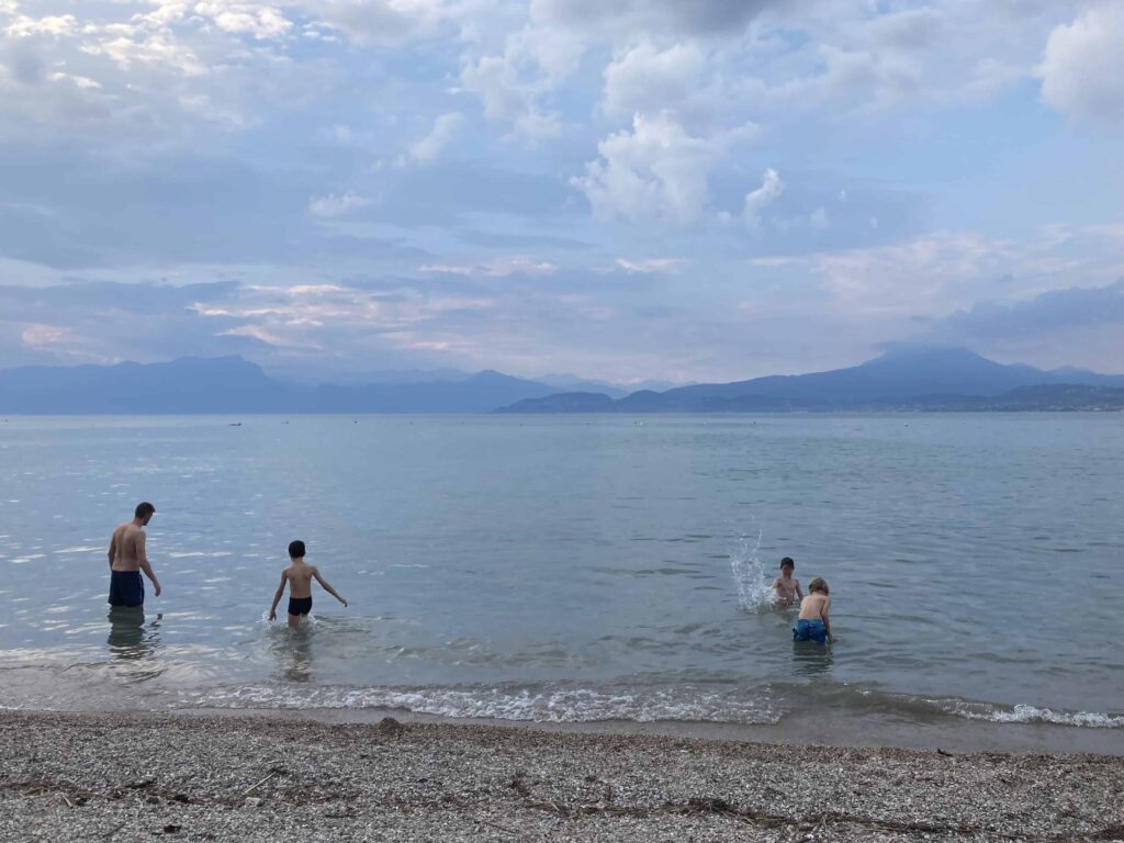 Kids and father splashing at beach on Lake Garda