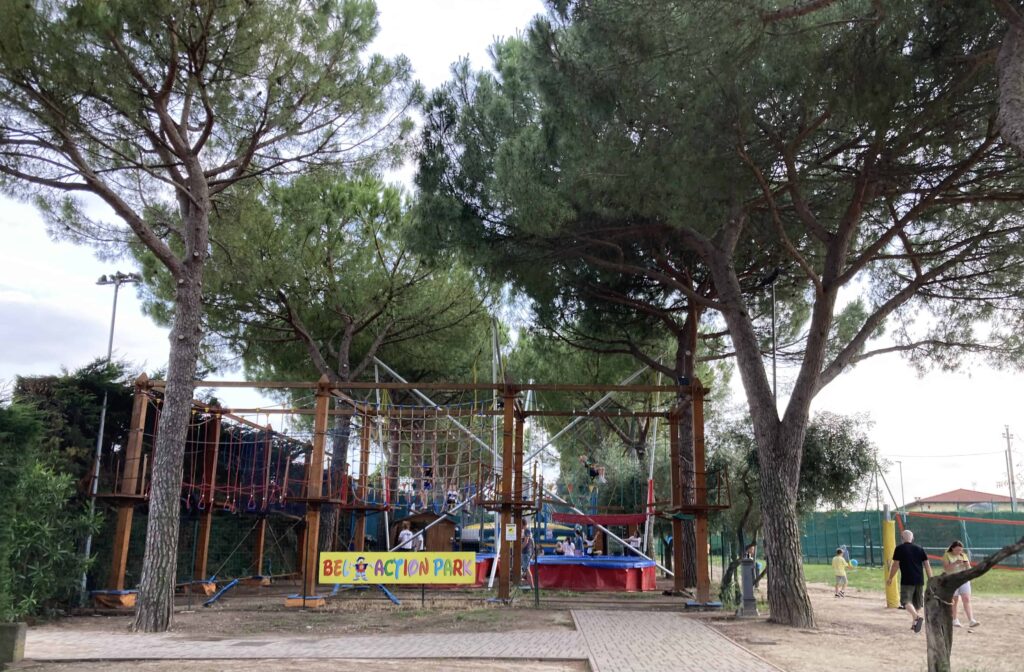 Play area at Camping Bella Italia in Lake Garda. Shaded by umbrella pines.