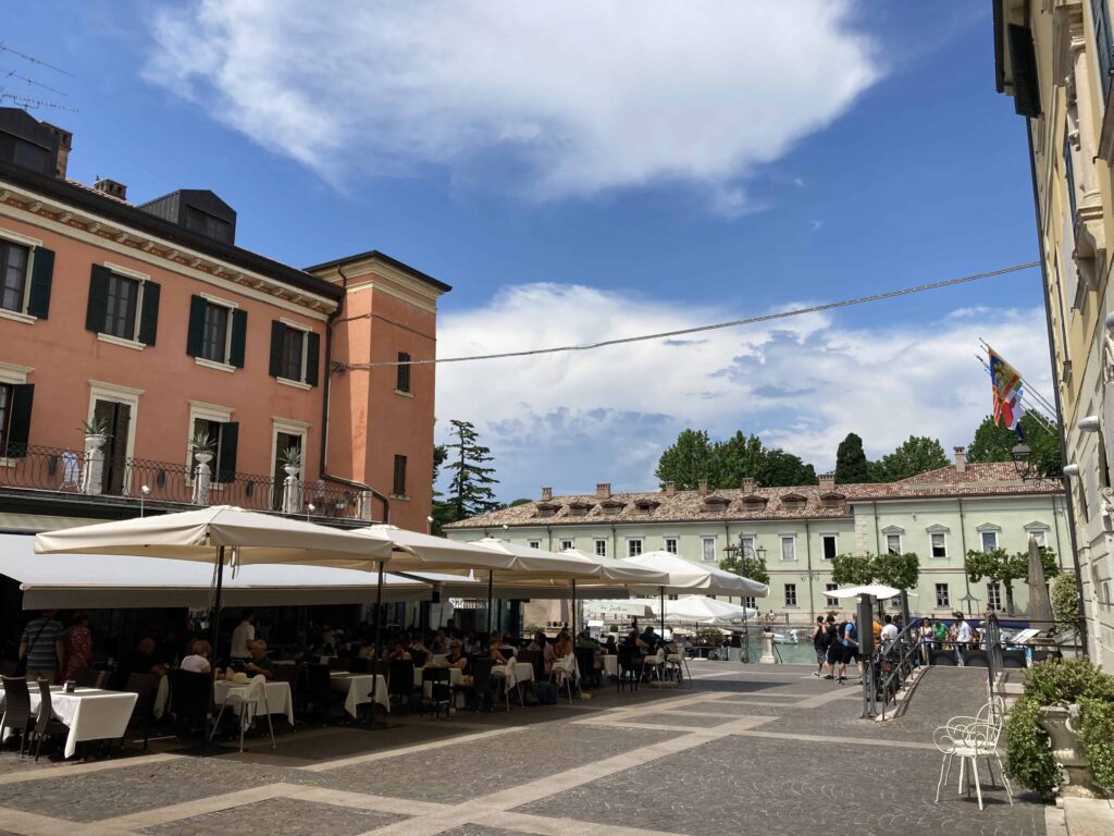 Piazza in Peschiera del Garda. Buildings and people dining outdoors.