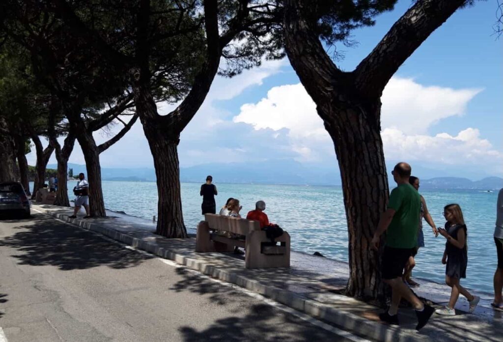 People walking and sitting along the lakefront in Peschiera del Garda