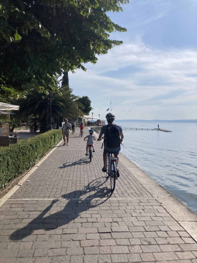 Father and son ride bikes along the Bardolino lakeside path