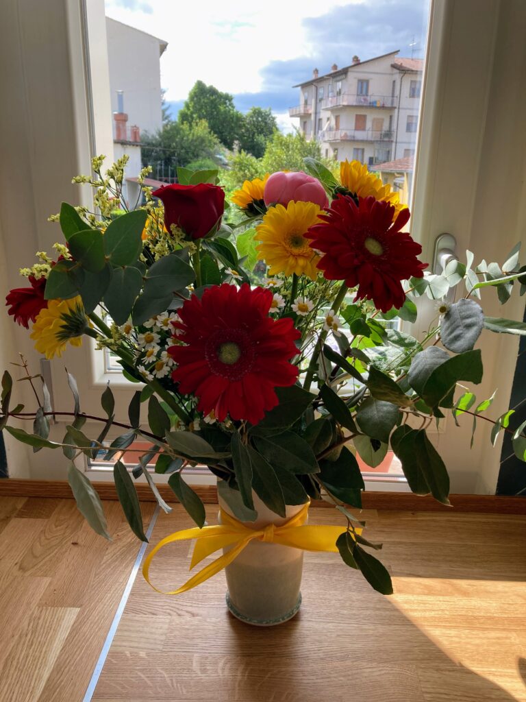 Vase of colorful flowers by a window in Italy.