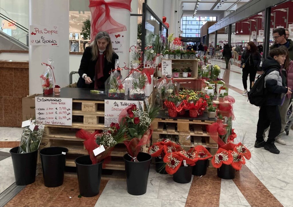 Woman running a stand selling Valentine's Day flowers at a shopping center in Italy.
