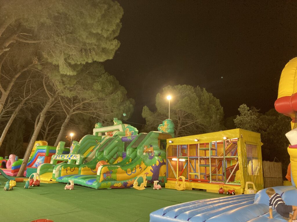 Bouncy castles in the evening . Umbrella pines on left.