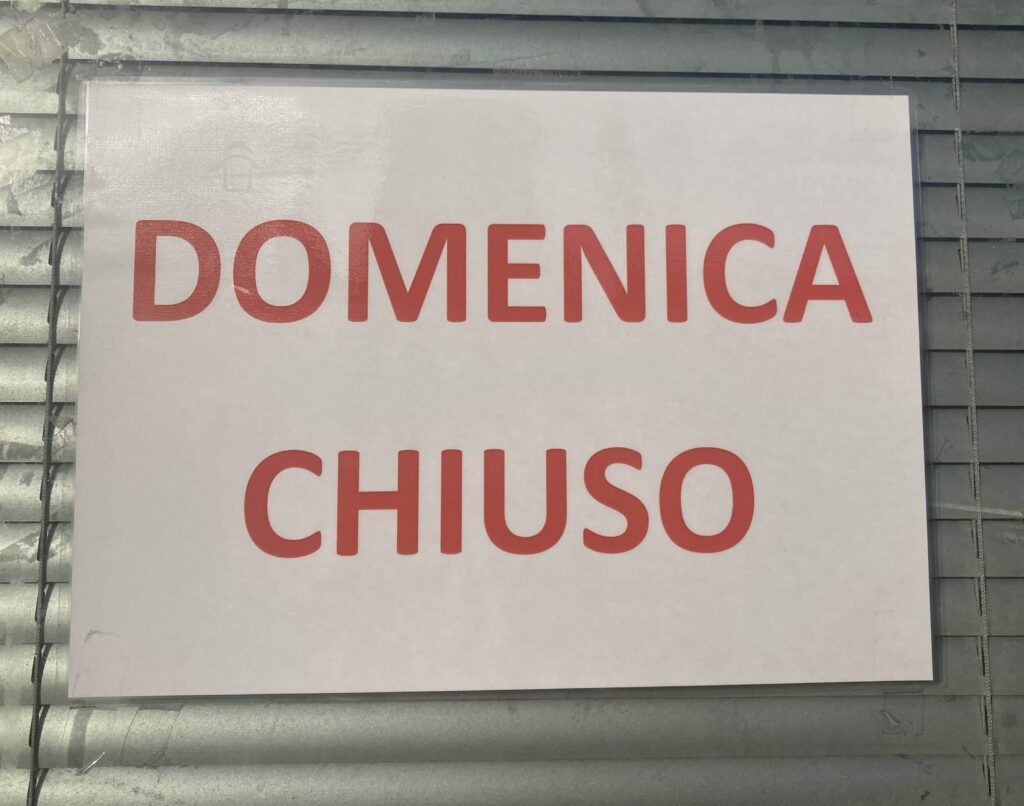 Sign in window with red letters, 'Domenica Chiuso.'