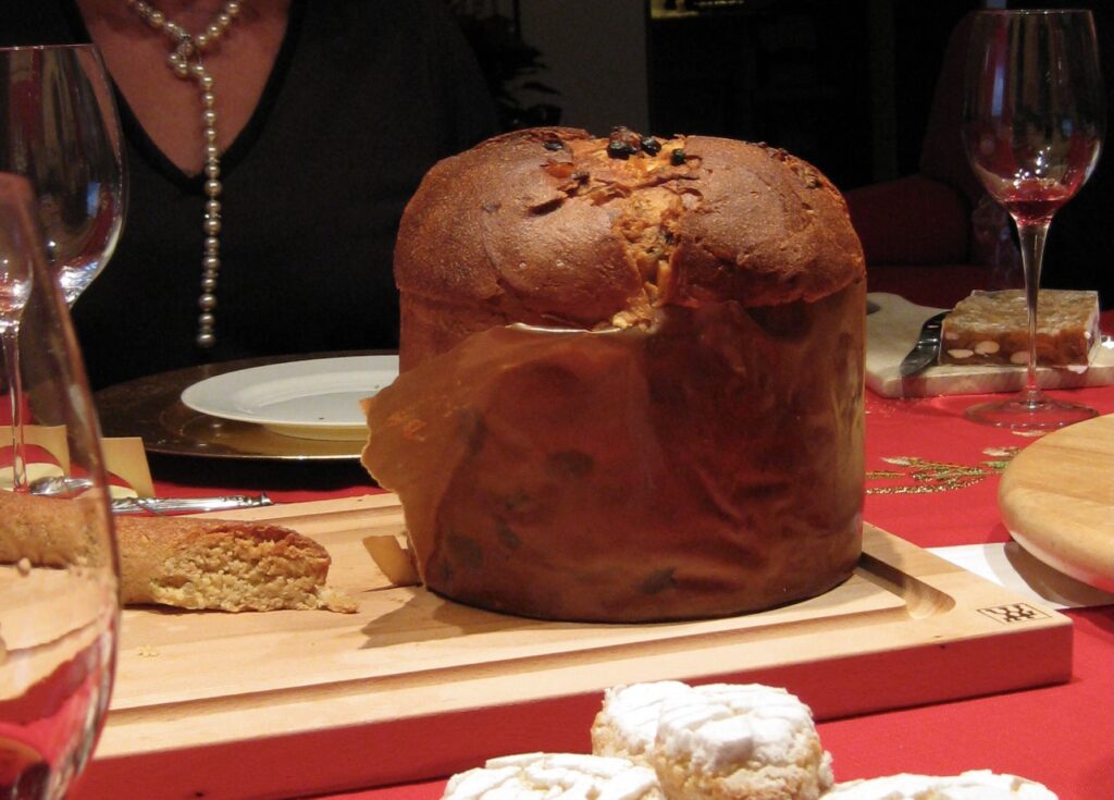 Panettone on a wooden cutting board at a Christmas dinner table in Italy.