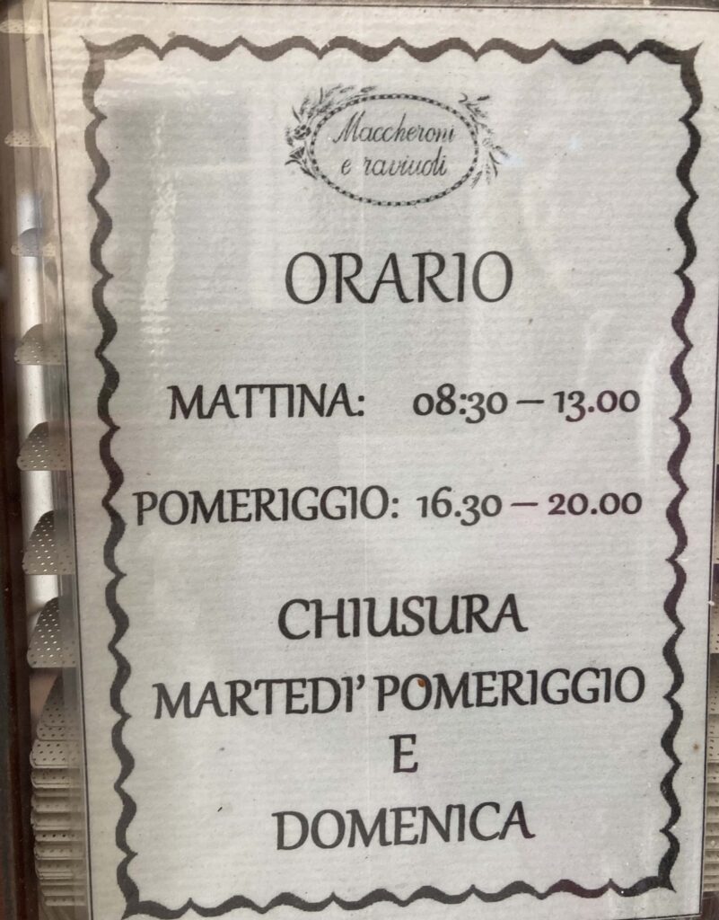 Sign in restaurant window in Italy listing opening and closing days and hours.