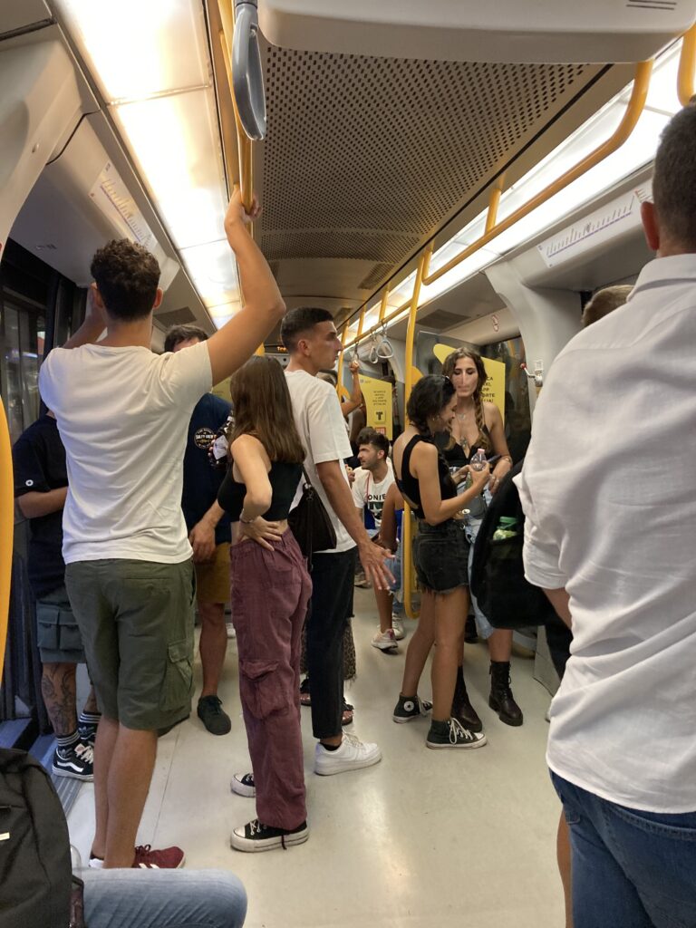 Inside a car on the Milan metro. People stand and sit.