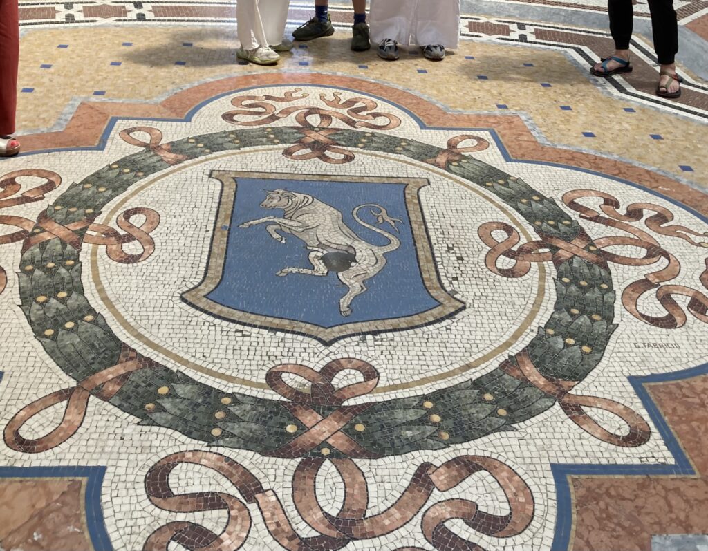 A mosaic on the ground with a bull in the middle.